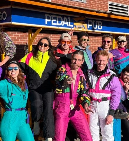 friends dressed up in ski suits around party bike