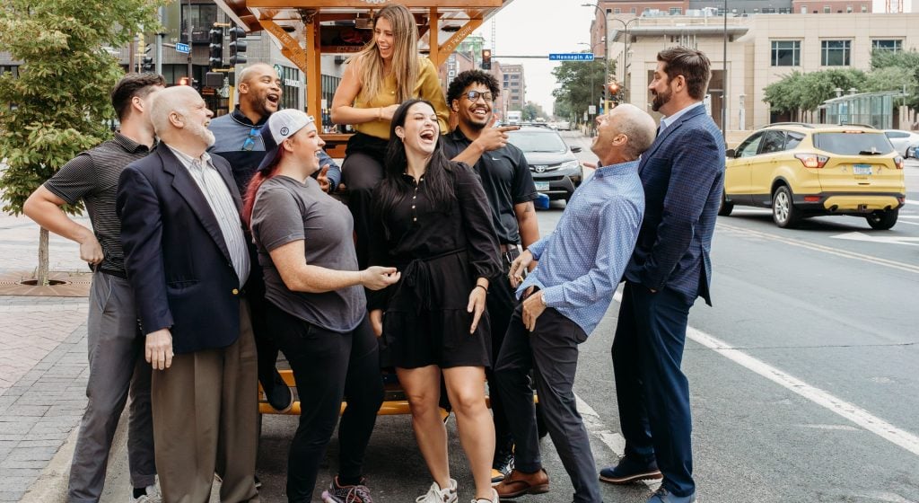 corporate team laughing in front of pedal pub bike