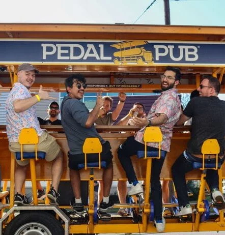 group of friends smiling on pedal pub bike