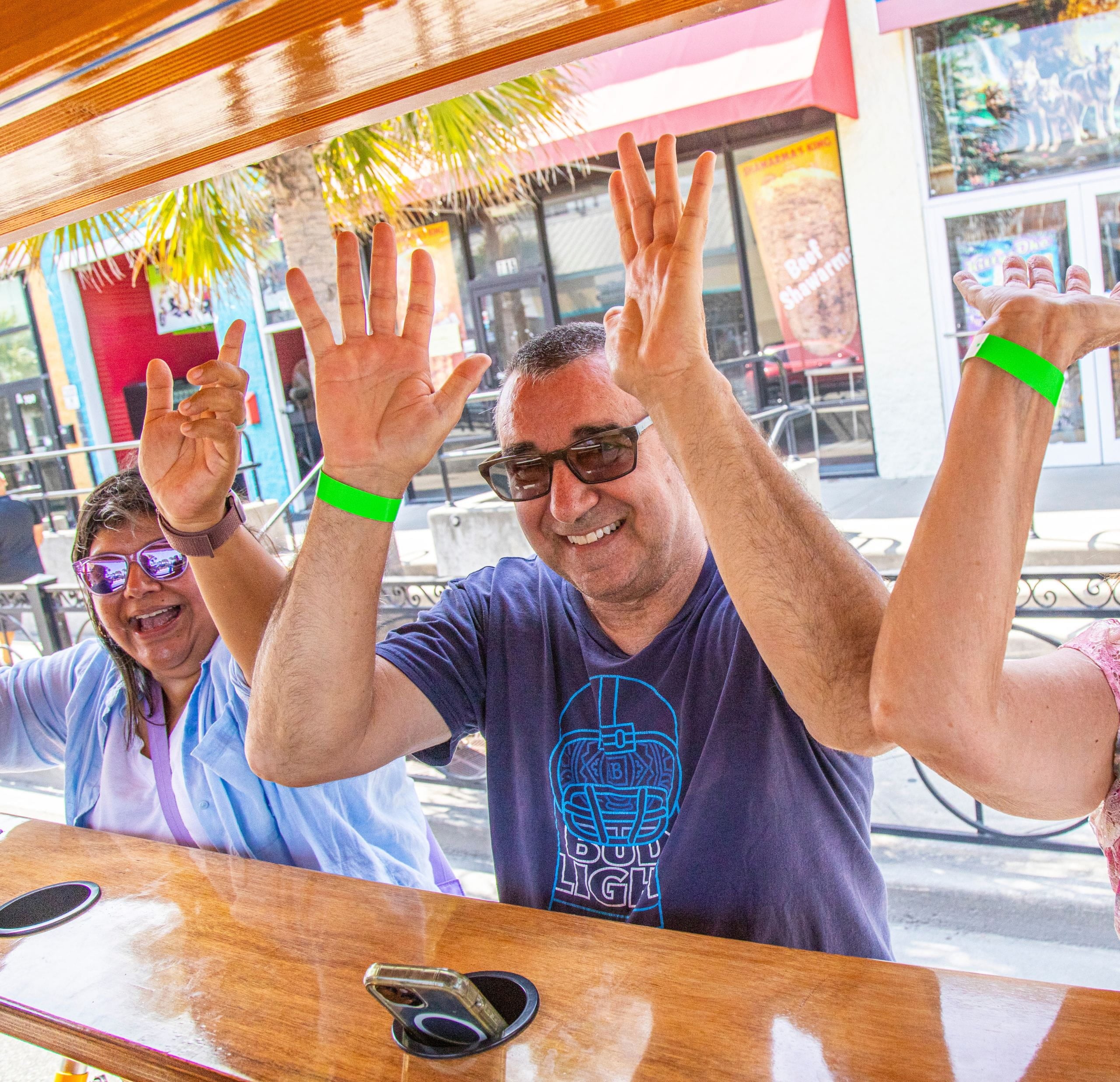 friends posing with their hands up on party bike