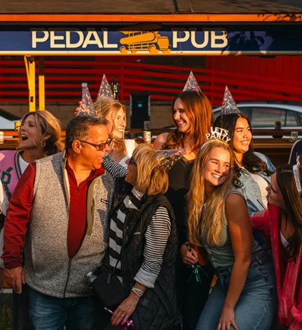 birthday party guests posing in front of Pedal Pub bike