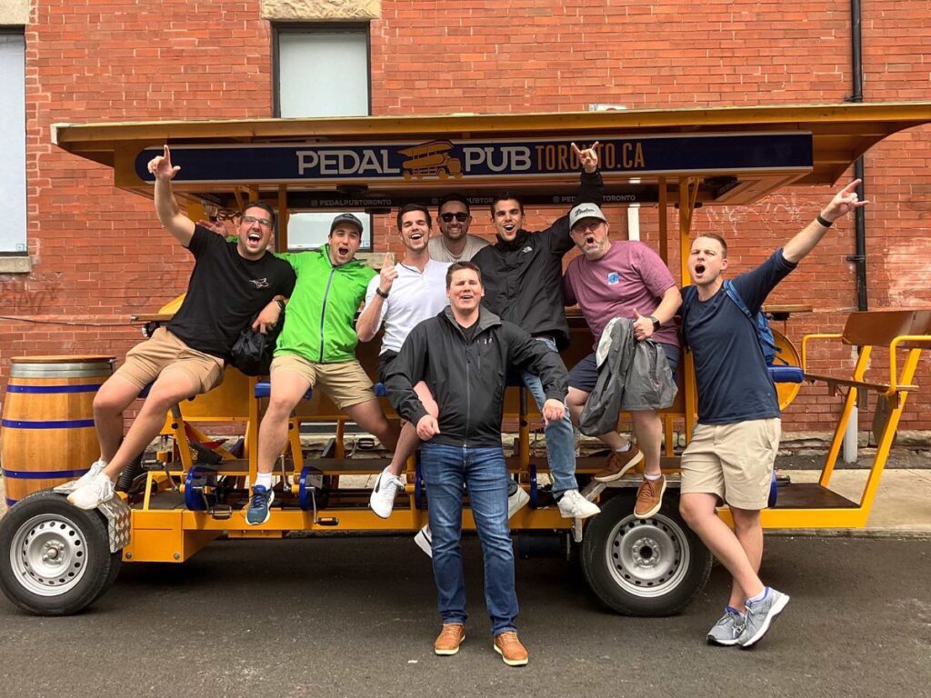 men seated and standing around party bike