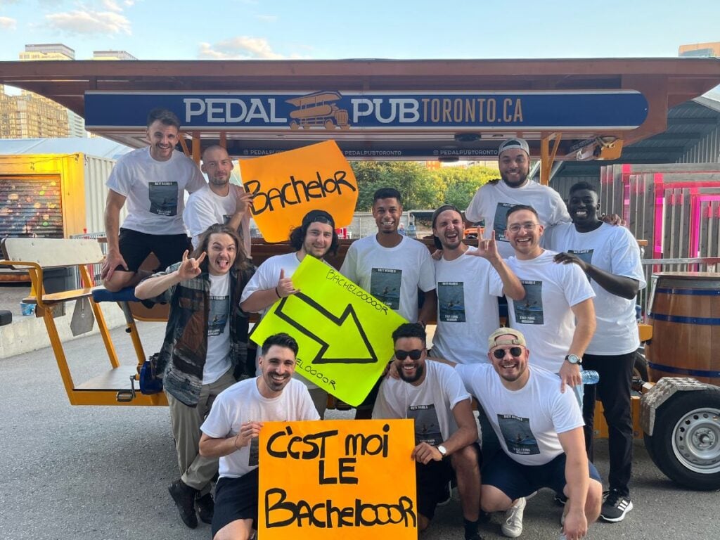 bachelor party holding signs in front of party bike