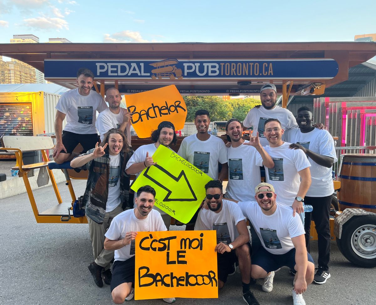 bachelor party holding signs in front of party bike