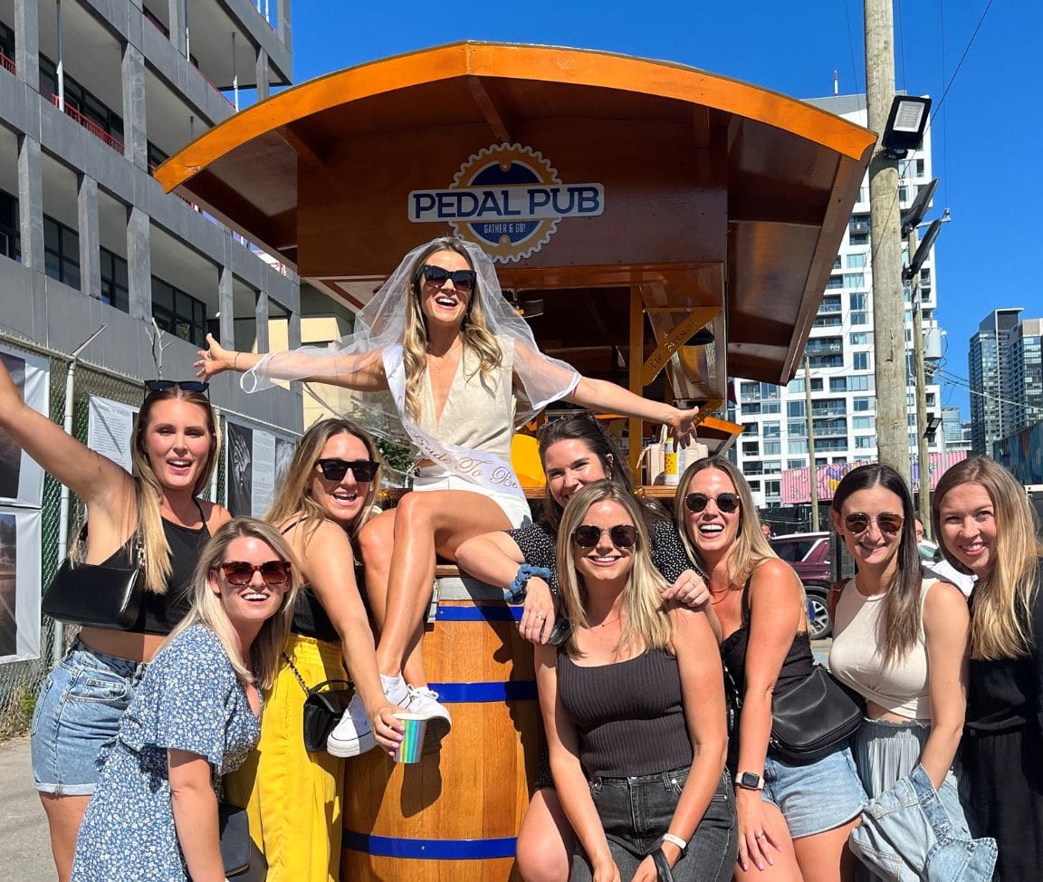 bachelorette party seated and standing around Pedal Pub Toronto