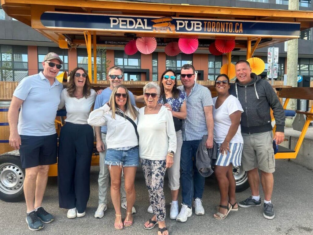 Bachelor party group at the Pedal Pub Toronto location, celebrant in pink wig standing on top of the bike while the group cheers below
