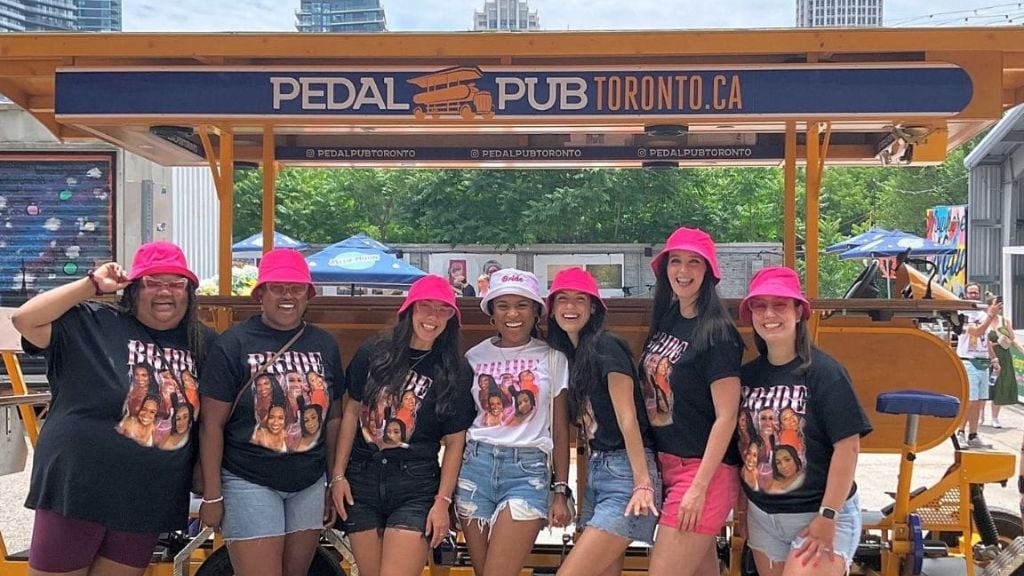 bachelorette party in matching shirts in front of party bike