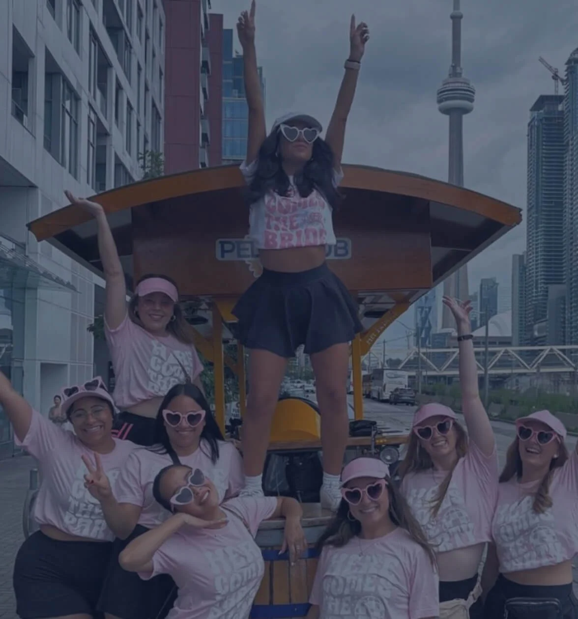 Bachelorette group posing in front of a Pedal Pub Toronto party bike on a private tour in downtown Toronto