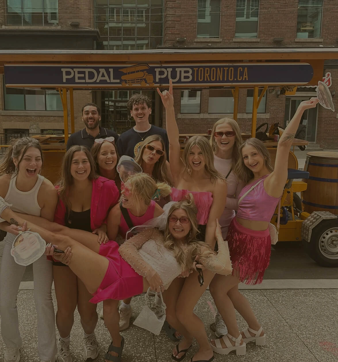 Bachelorette group posing in front of a Pedal Pub Toronto party bike on a public tour in downtown Toronto