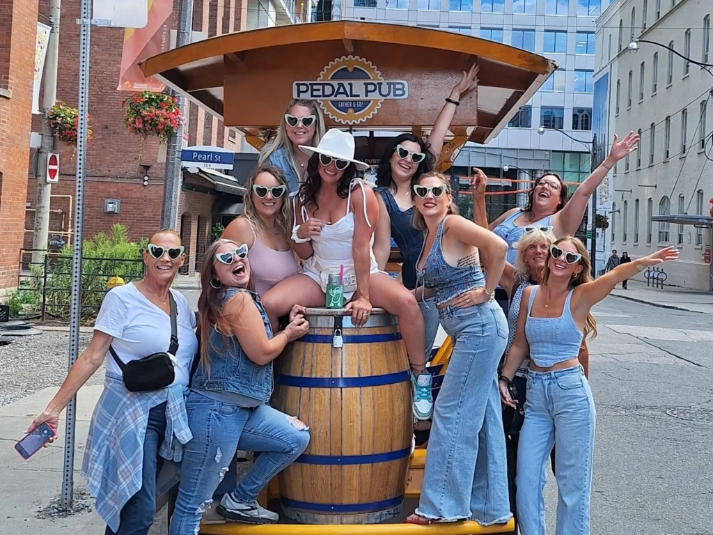 Bride in white hat with friends in denim and heart sunglasses on a Pedal Pub Toronto bachelorette party