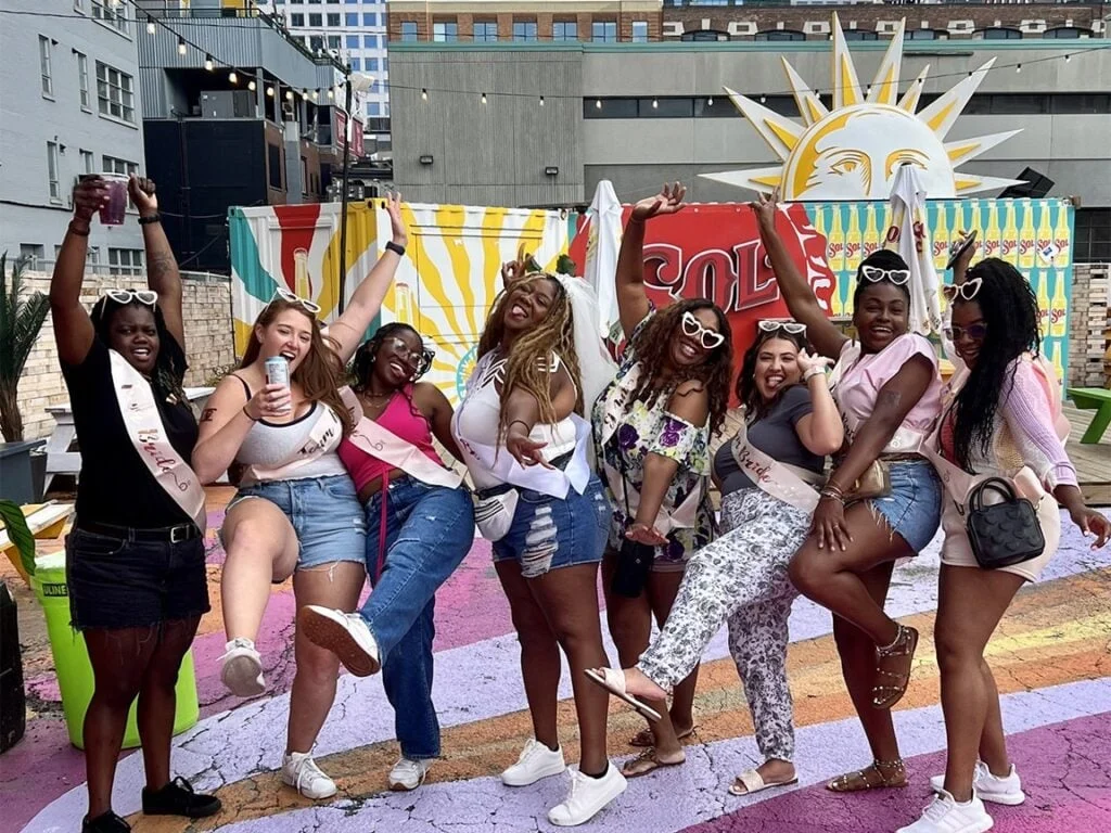 Bachelorette group in sashes posing at a colorful patio stop during a Pedal Pub Toronto tour