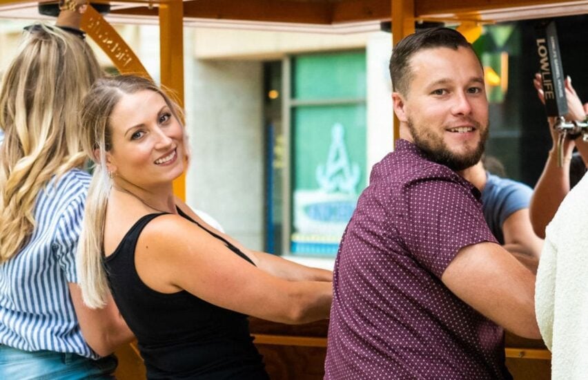 close-up of couple sitting on pedal pub bike smiling