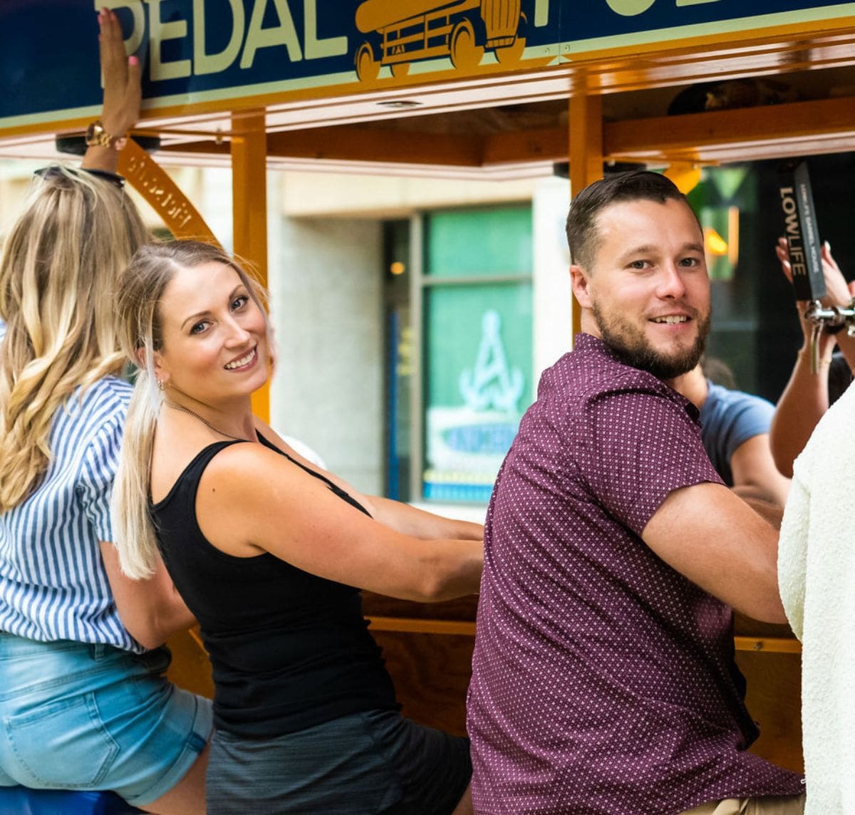 close-up of couple sitting on pedal pub bike smiling
